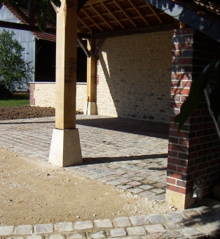 Aménagement d'un auvent en maçonnerie de pierre apparente, brique flammée et pavage en pierre à Corancez